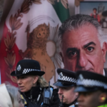 Police officers in uniform chatting in front of a large portrait and a Mexican flag backdrop.