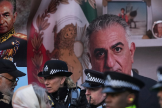 Police officers in uniform chatting in front of a large portrait and a Mexican flag backdrop.